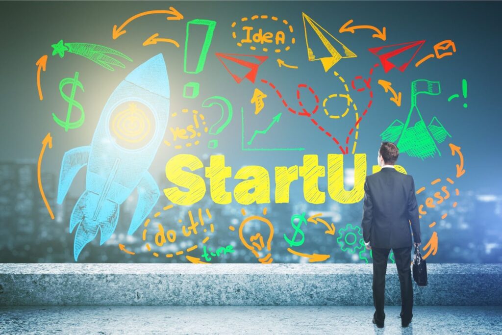 A businessman looks at a vibrant illustration with a rocket ship, growth symbols, and "Startup" in yellow, representing innovation in digital marketing for startups.