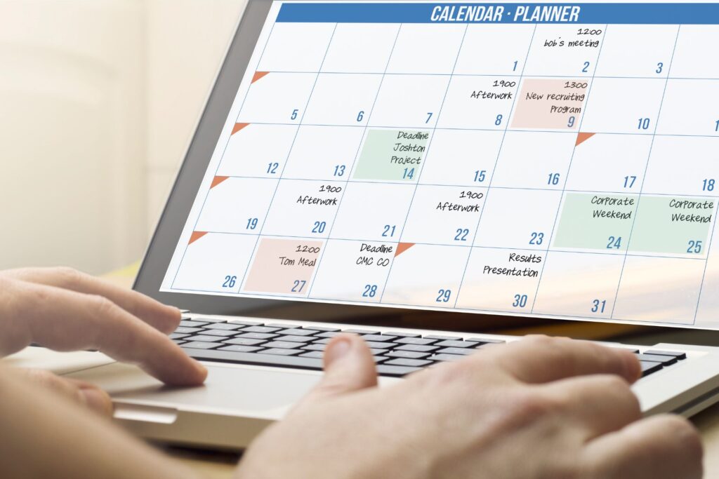 A laptop displaying a content calendar filled with deadlines, and marketing-related events.