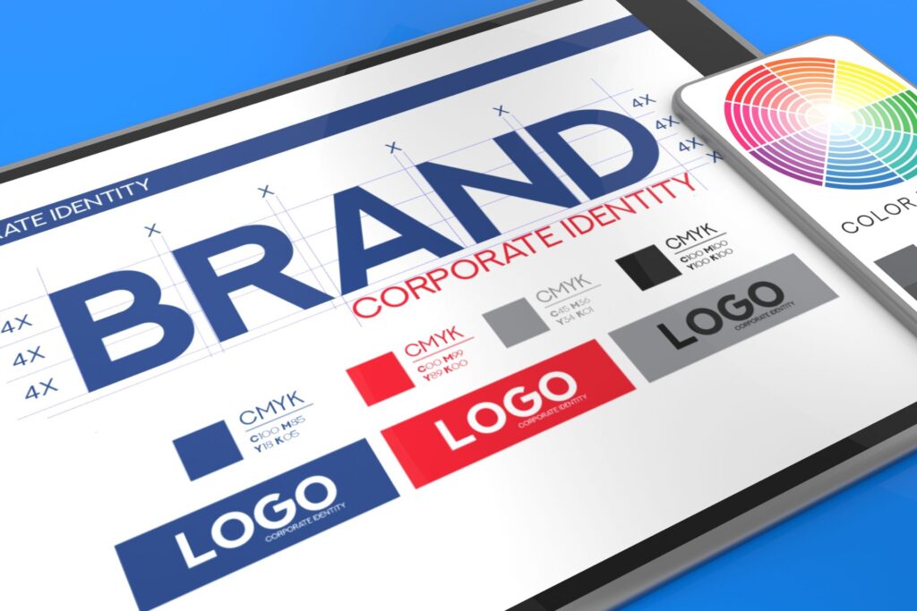 Tablet displaying a Spark Collective brand guide with color swatches, CMYK values, and logo variations. A smartphone nearby shows a color wheel. The image highlights visual consistency in branding.